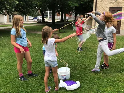 Children playing with bubbles on the grass outside the Woodstock Museum